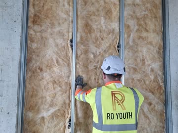 RO Youth operative fitting insulation between metal studs