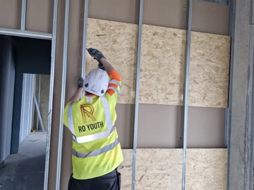 RO Youth operative fixing board to a framed wall